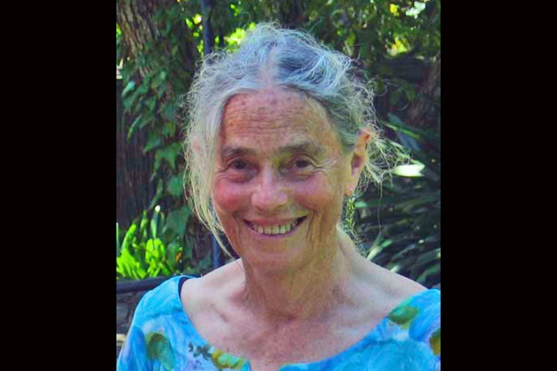 Head and shoulders of a woman with grey hair smiling at the camera.
