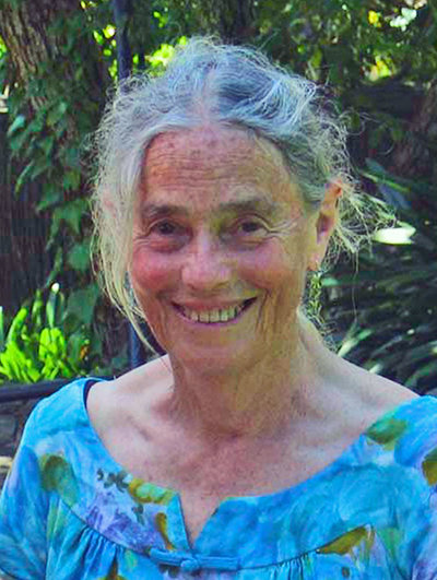 Head and shoulders of a woman with grey hair smiling at the camera.