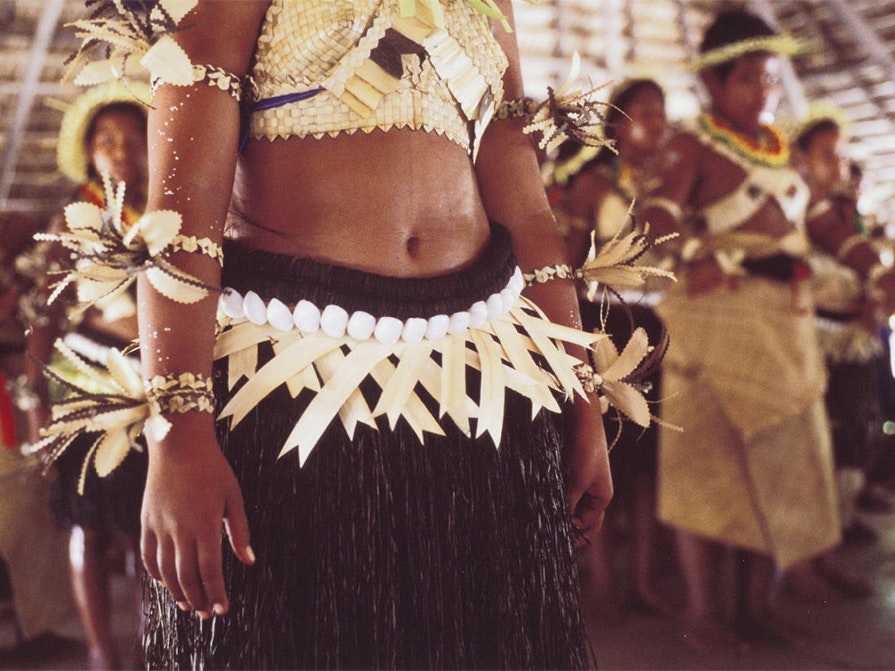 Female dance belts of coconut, shell, and palm frond, July 1999, Kiribati, by Tony Whincup, type C print. Te Papa (O.033028) A view of a woman's torso. She is wearing a traditional clothing.