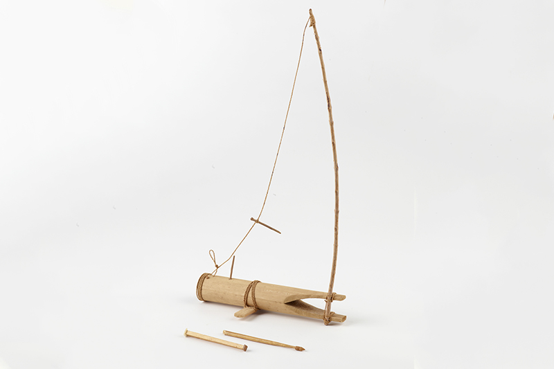 A short piece of bamboo tube with a long stick protruding from one end that is tied with cord.