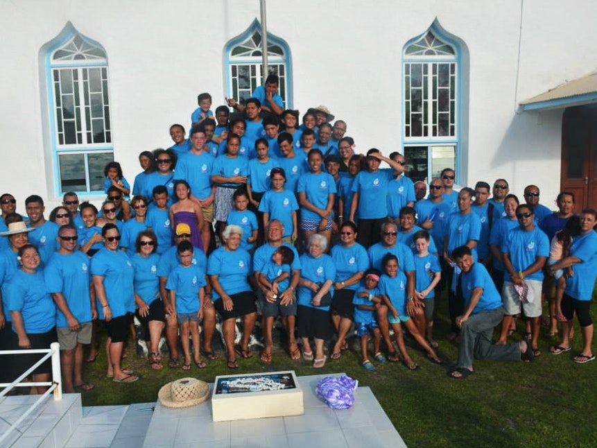 Tuaine-Nurse Robati’s kopu tangata, taken in front of the Arorangi church, Rarotonga. Photo courtesy of Tuaine-Nurse Robati A large group of people are assembled in front of a church. Nearly all of them are wearing the same bright blue coloured shirt.