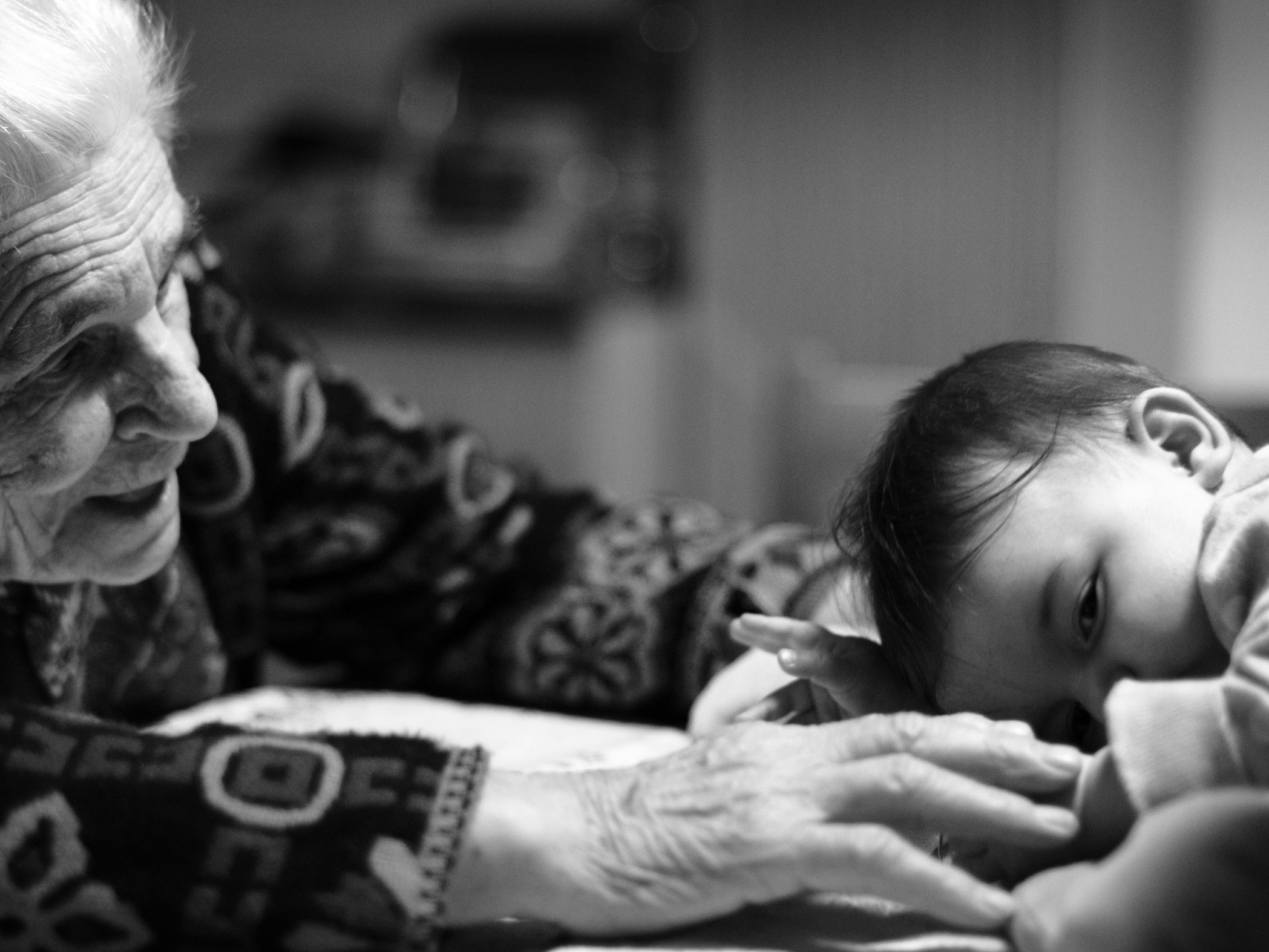 Photo by Paolo Bendandi. Unsplash An elderly woman is reaching out to a small baby child who is lying on its stomach.