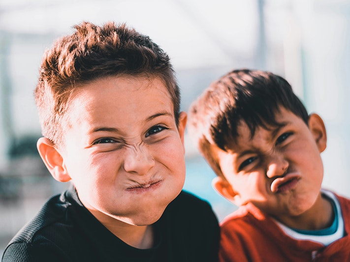 Photo by Austin Pacheco. Unsplash Close up of two children making faces at the camera.