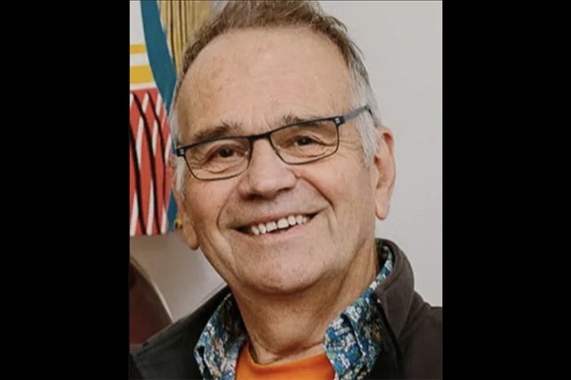 Head and shoulders of an older man wearing glasses and smiling at the camera.