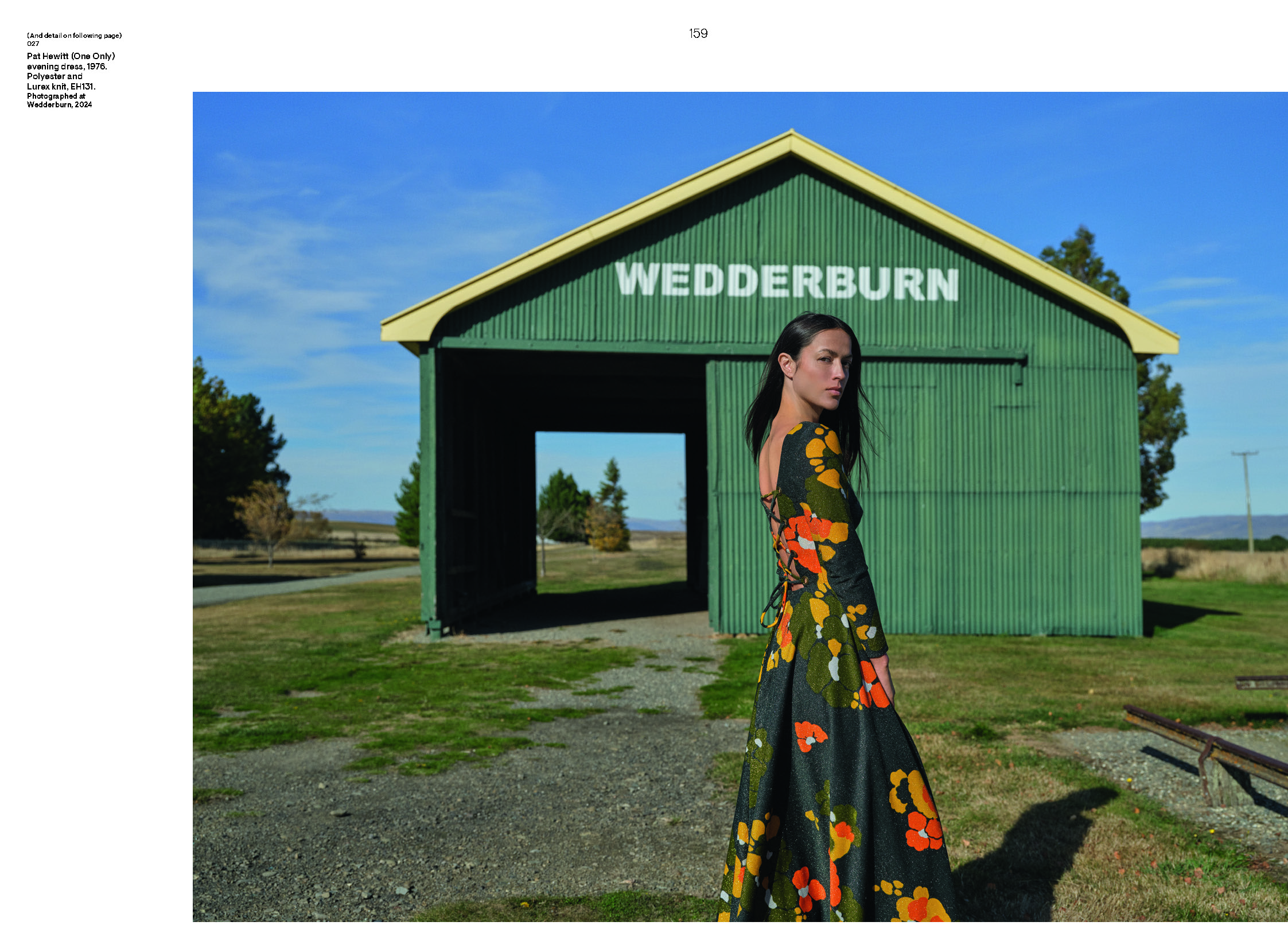 A page of a book with 80% of the page taken up by a photo of a woman standing in front of a green shed with the word Wedderburn painted on it. She is wearing a longsleeved long dress that is green with yellow and orange flowers on it.