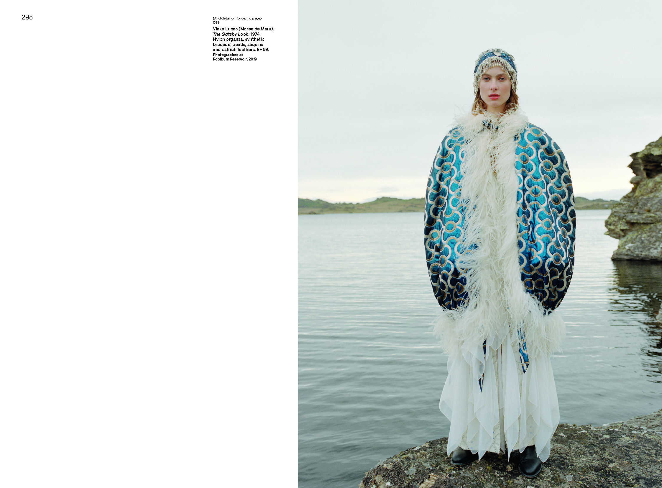 A page in a book with some text and a photo of a woman standing beside a lake who is wearing a long white dress with a blue and silver pattered oversized cape that has white feather trim.