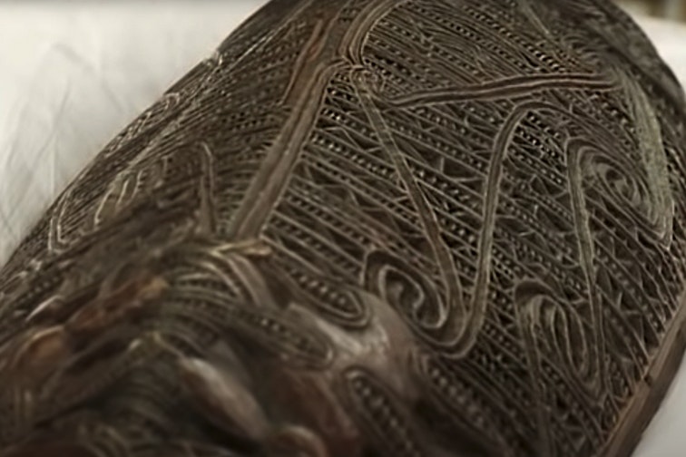 A close view of a carved wooden vessel.