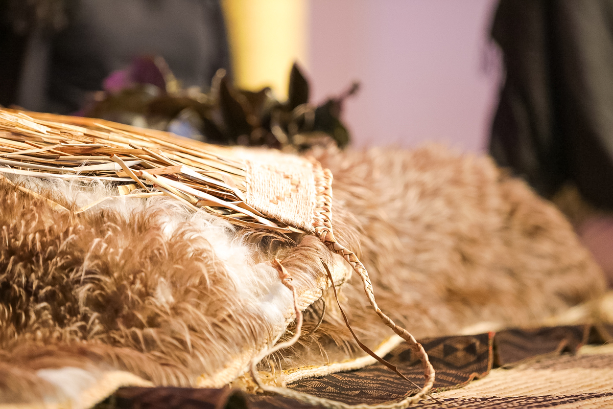 Kakahu in foreground, with mats underneath and flowers blurred in background