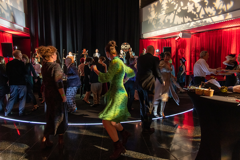 People dancing in a space surrounded by red curtains.