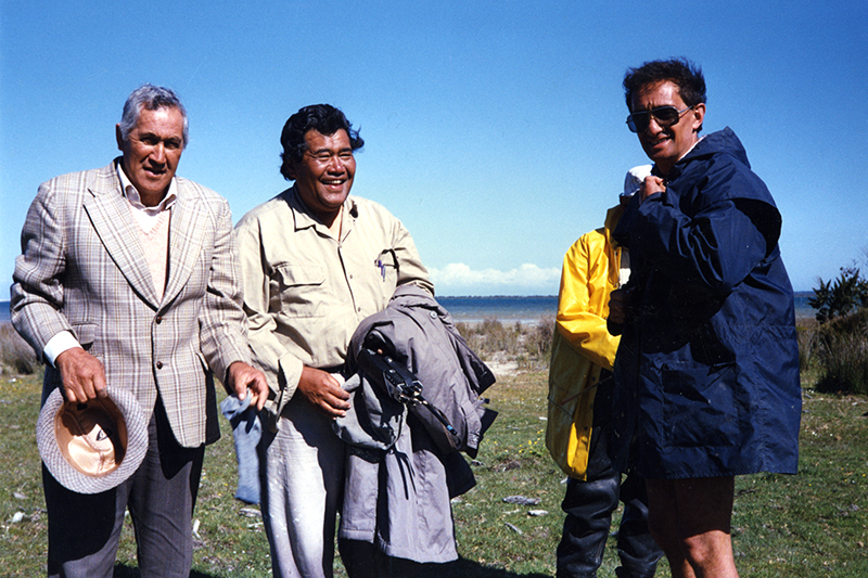 Three men are standing near a beach.