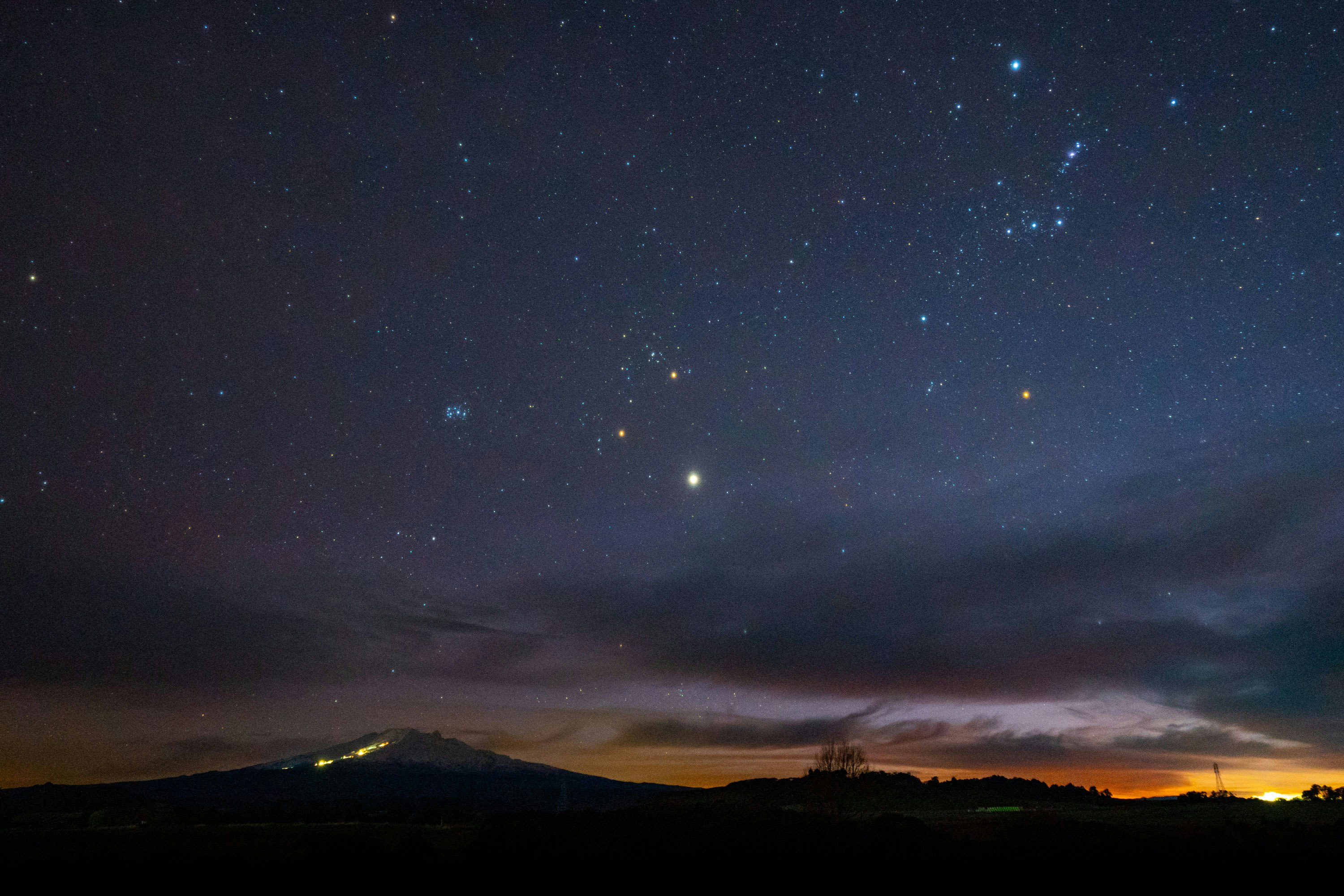 A night sky with stars visible and start of a sunrise.