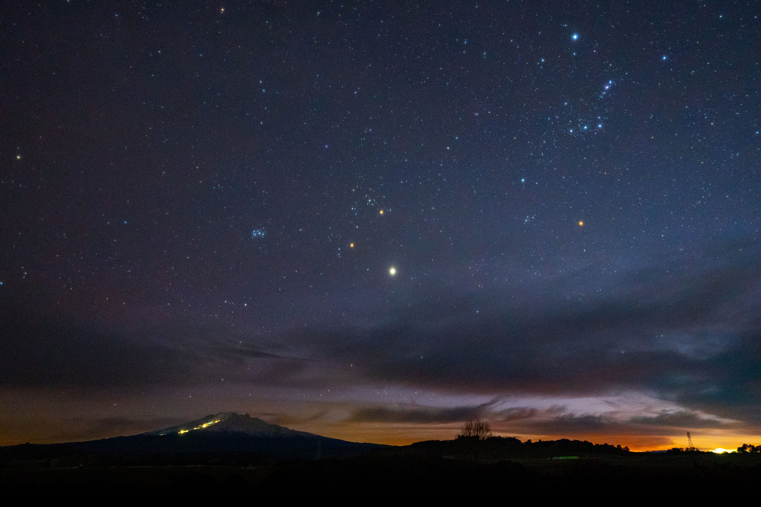 A night sky with stars visible and start of a sunrise.