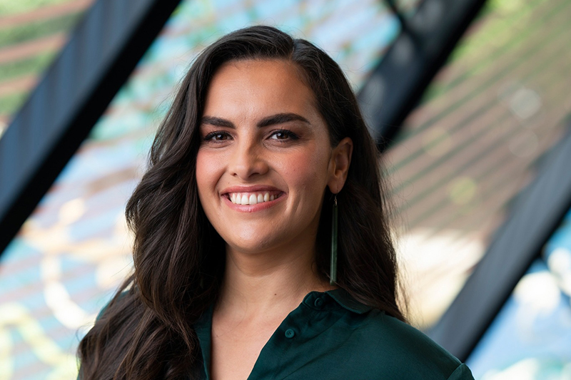Head and shoulders of a woman with long dark hair smiling at the camera.