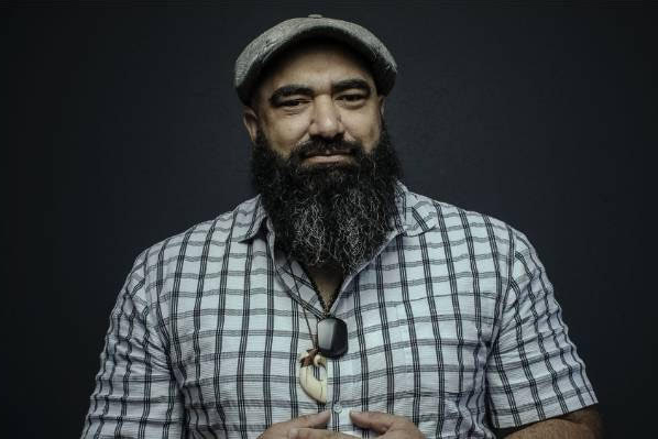 Head and shoulders of a man with a beard wearing a cap and smiling at the camera.