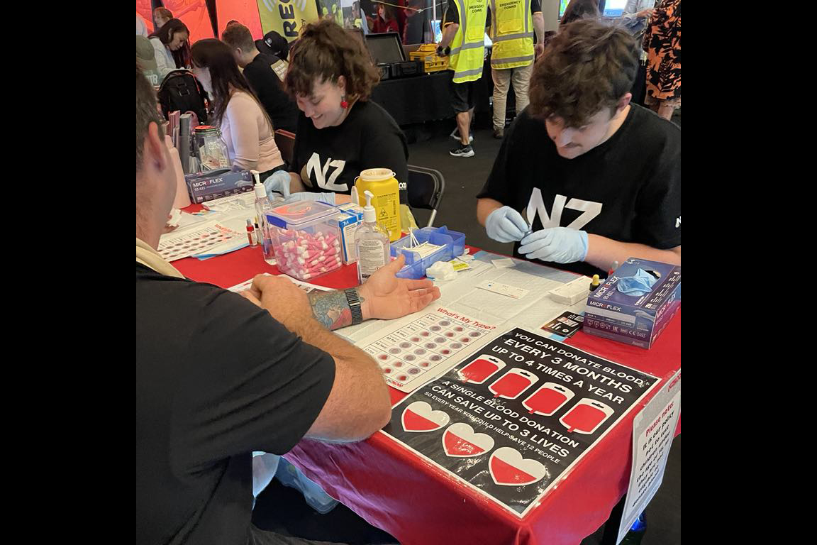 People sitting at a table with charts and blood-testing equipment in front of them.