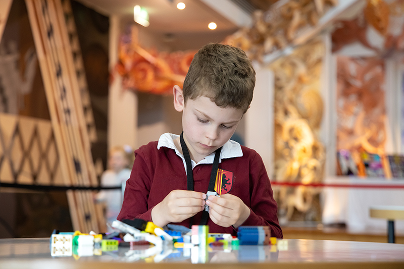 A child is playing with Lego at a table in the Te Papa marae.