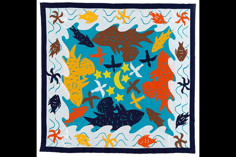 A patchwork quilt with stylised fish, stars, moon, waves, and seaweed images.