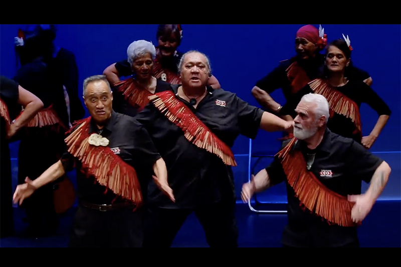 Several older people performing kapa haka Māori performance on a stage.