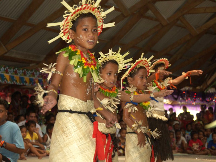 Mwaie Bikenibeu 2012 dance stills, Tony Whincup, Kiribati. Gift of Tony Whincup estate, 2017. Te Papa (O.047354) Children in traditional Kiribati costume are performing for people.