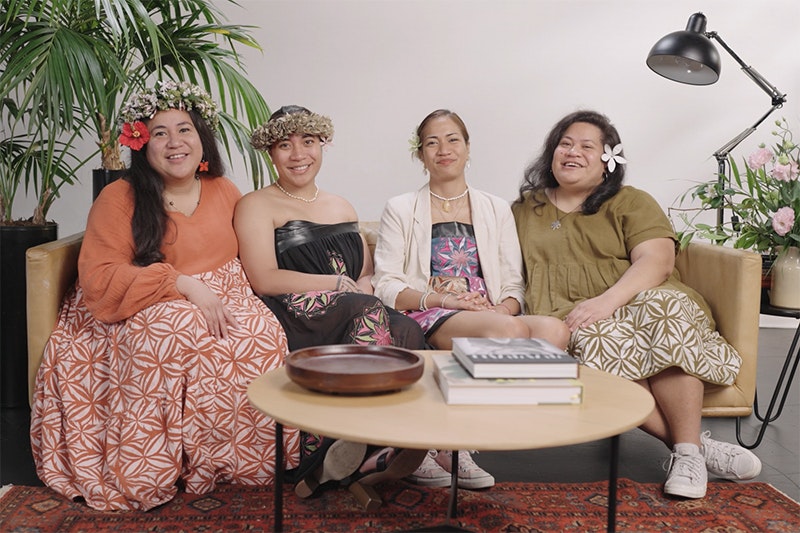 Four women sitting on a sofa smiling at the camera.