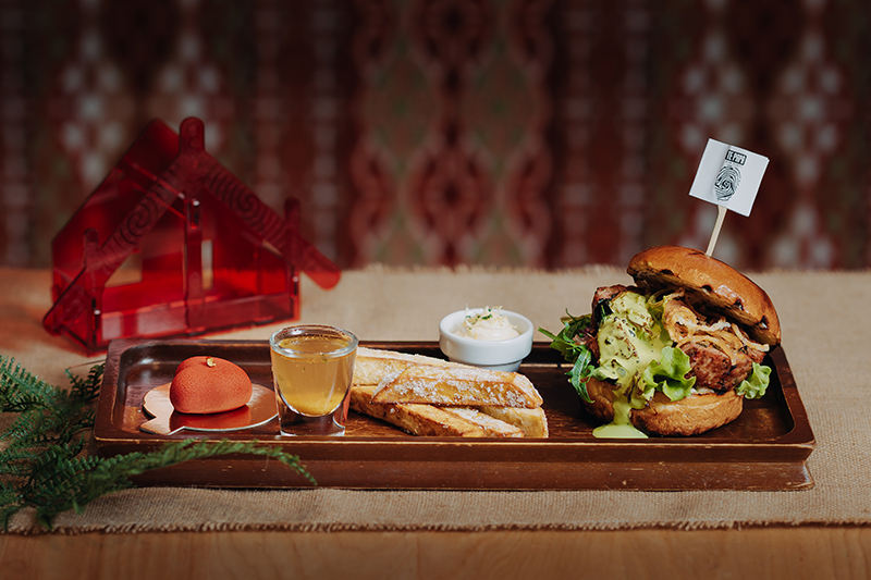 A meal including a burger, some bread, and a heart-shaped desert on a platter on a table.
