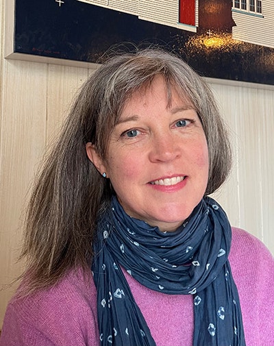 Head and shoulders shot of a woman who is wearing a pink shirt and patterned scarf