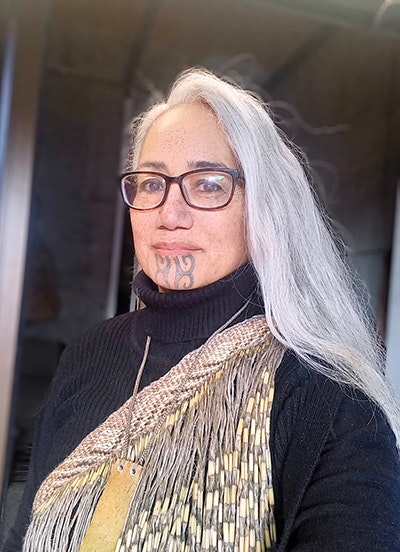 Close-up view of woman with long grey here and moko kauae