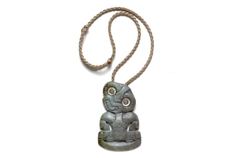 A pounamu or New Zealand Greenstone pendant in human form with a woven cord.