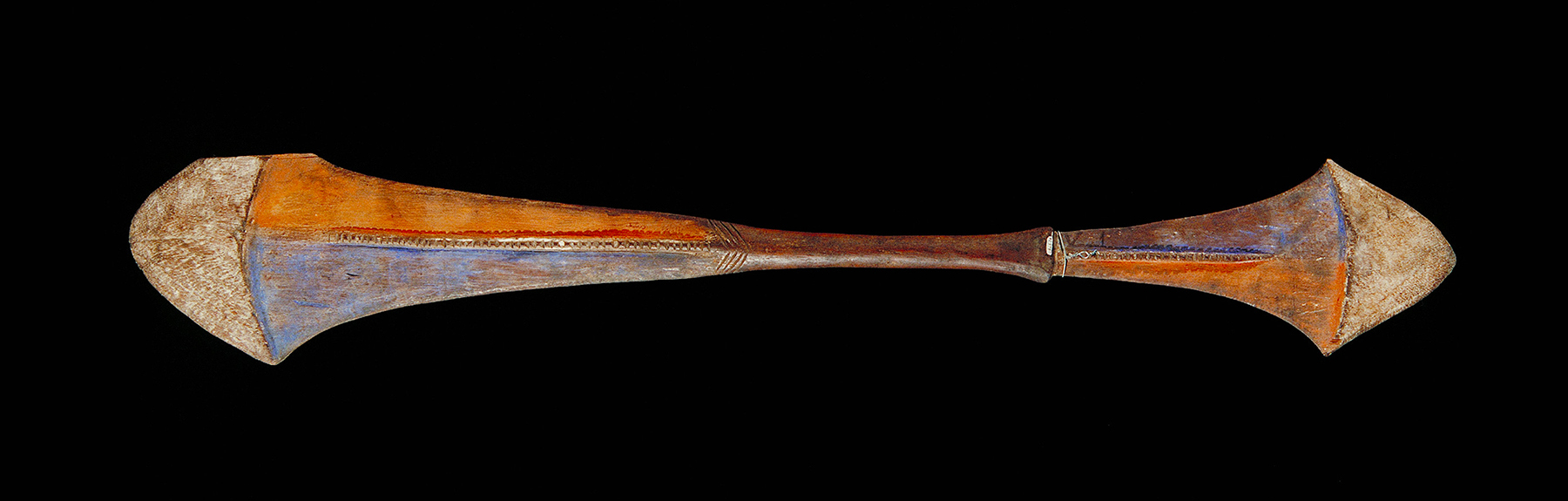 A wooden paddle with one side bigger than the other and painted orange and blue.