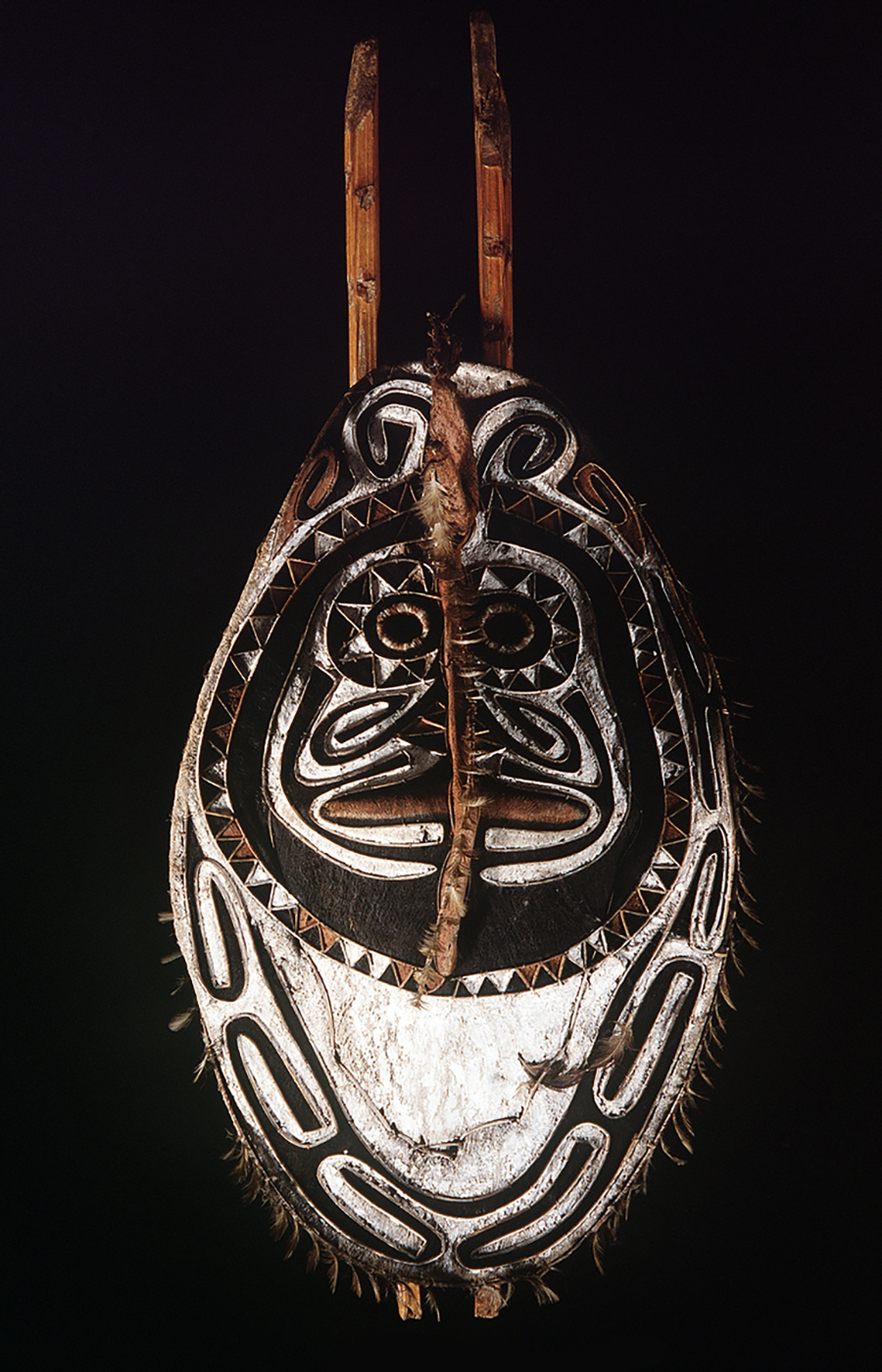 A round mask with two sticks pointing our of the top of the head.