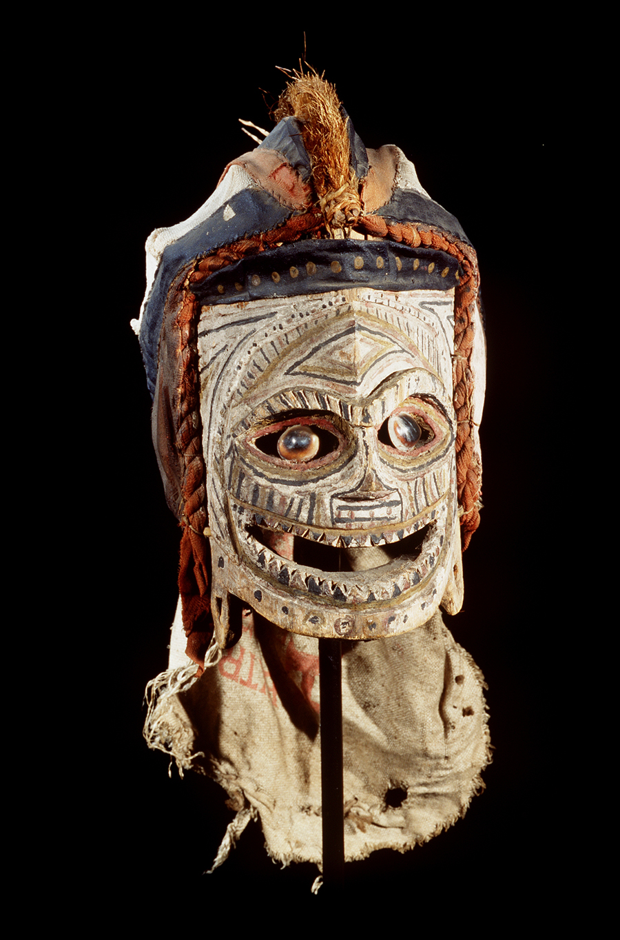 A mask with a helmet head sitting on a stand.