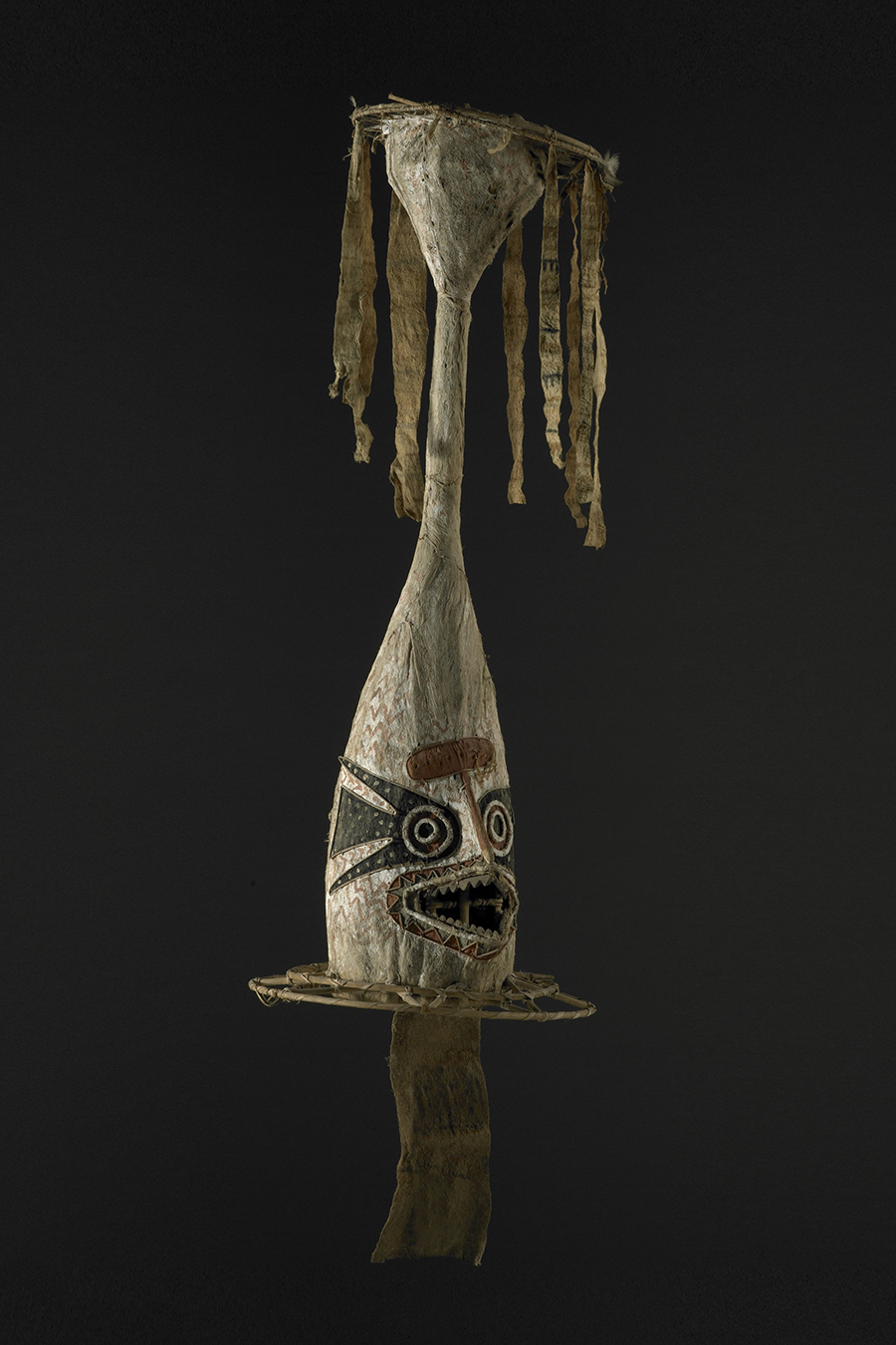 A tall mask with a turret at the top with barkcloth hanging off it.