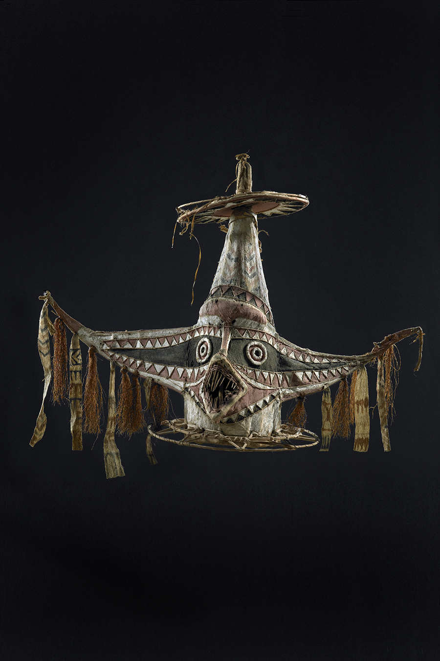 A mask made with tapa cloth with wide eye 'wings; and a round circle on the top