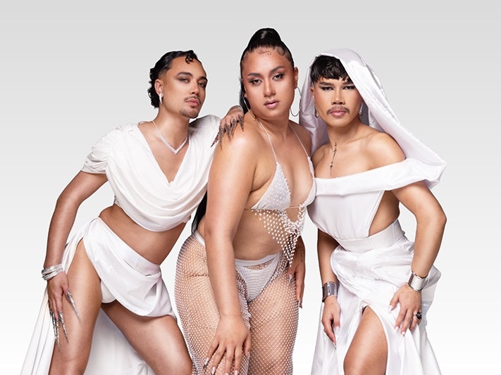 The Grand Kiki House of Marama Models (from left to right): Founding Mother Romé Marama, Godmother Hibiscus Marama, and Founding Mother Karamera Marama. Photo by Hohua Kurene Three people dressed in white cloth or clothing are posed together and staring at the camera.