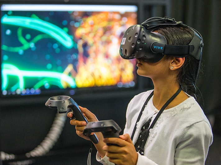 Te Papa Talks: Virtual Realities weekend, 2017. Photo by . Te Papa (1 A young child is wearing a Virtual Reality headset and holding two handsets.