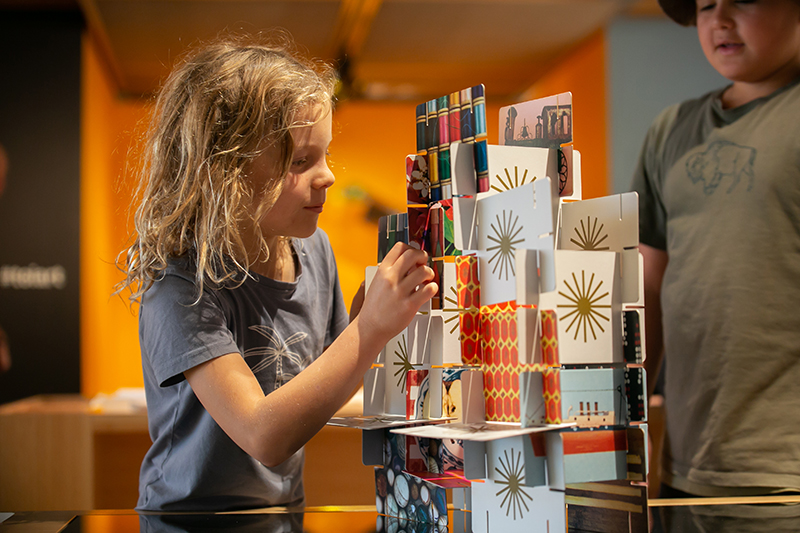 Two children are creating a tower out of cards.