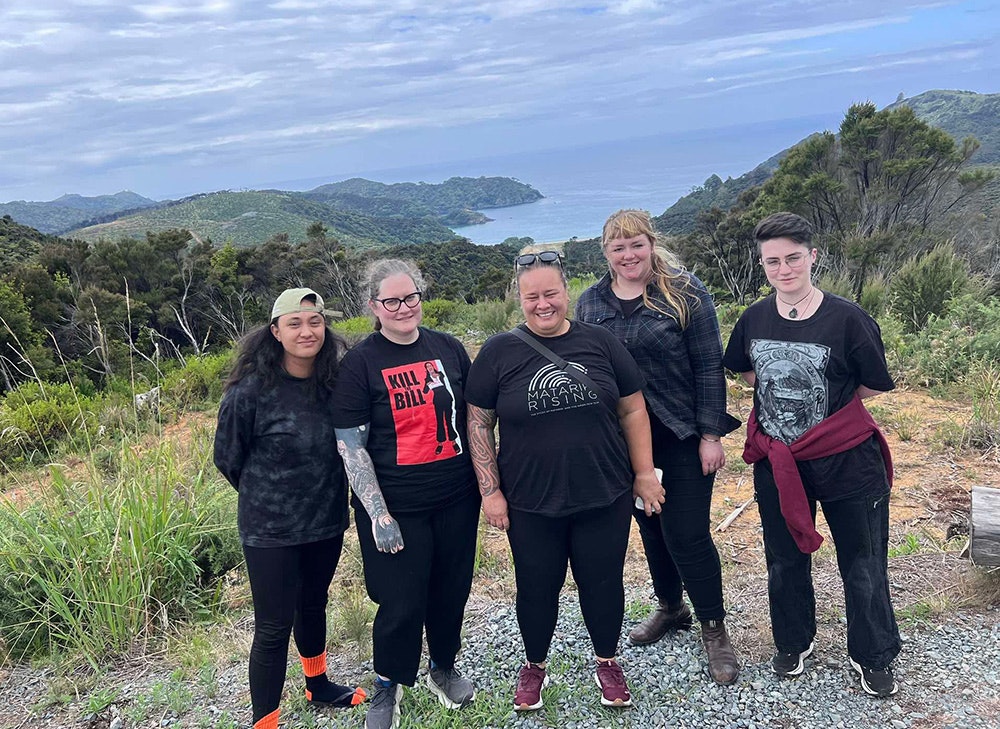 Five people standing on a mountain and smiling at the camera.