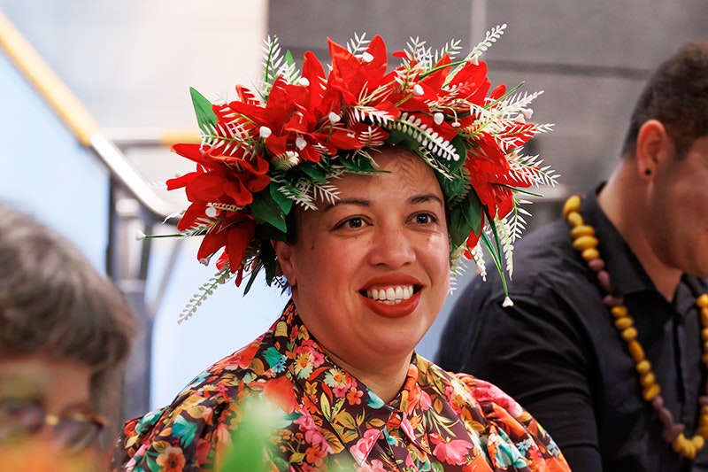 A woman is smiling at someone off camera. She has a floral wreath in her hair.