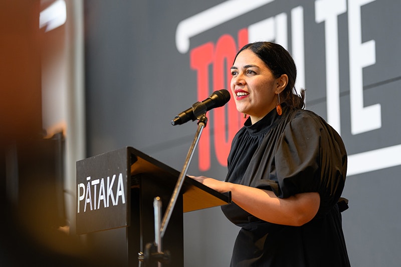 A woman is speaking from a podium to an unsees audience.