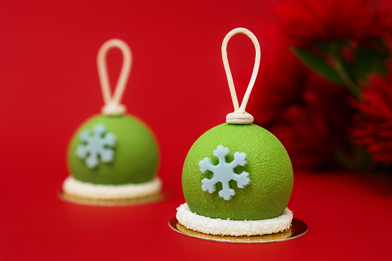 Two green desserts, shaped like bells with a blue snowflake on the front. 