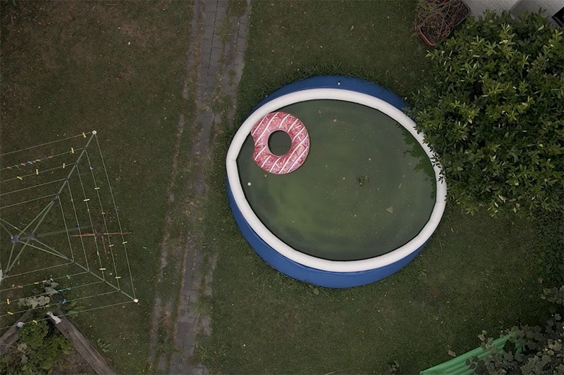 A top-down view of a back yard with a paddling pool and a rotary clothesline.
