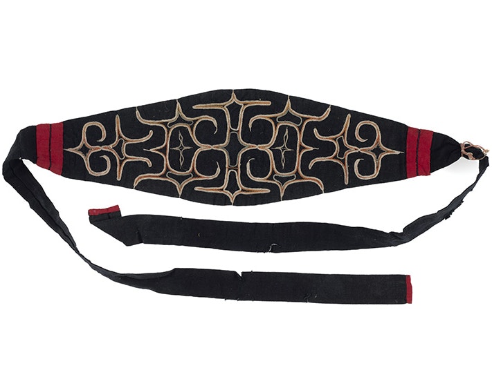 Matampus (Ainu headband), circa 1904, Japan, maker unknown. Gift of Mr K.C. Bibby, 1956. CC BY-NC-ND 4.0. Te Papa (FE003039) A red, black and gold headband with a wide middle and thin straps.