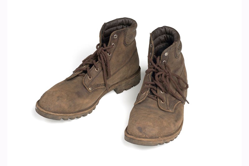 A pair of worn brown boots on a white surface.