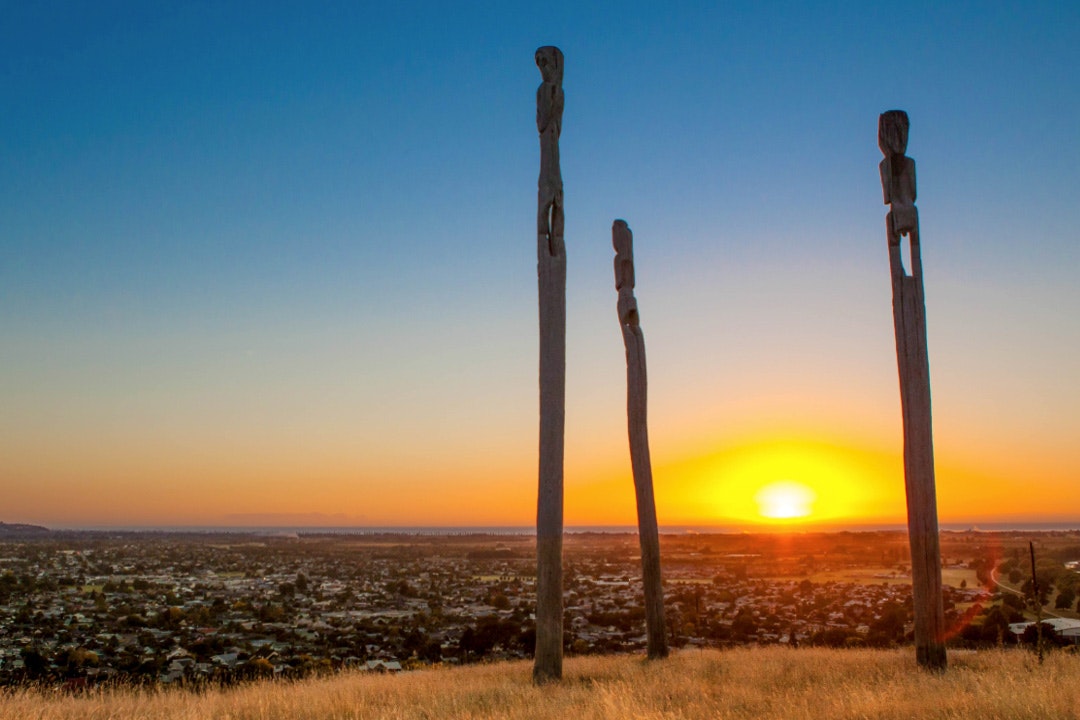 Three pou or poles standing on the top of a mountain at sunrise.