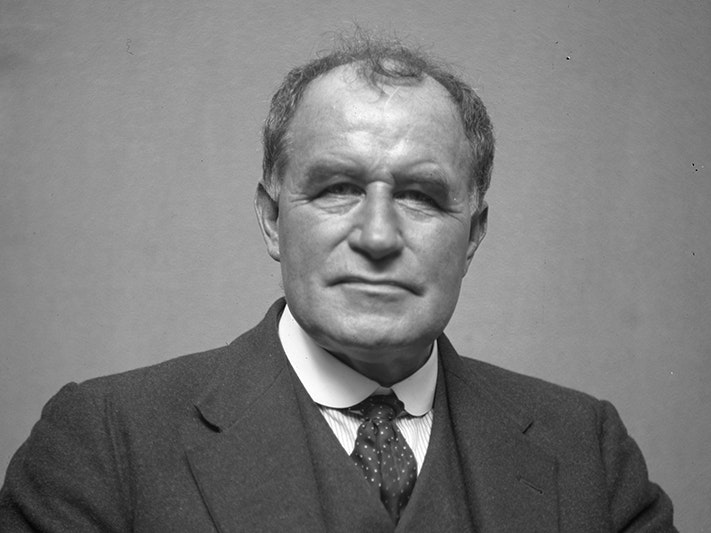 James Ingram McDonald, circa 1925, Wellington, by James McDonald. Te Papa (MU000523/001/0456) A black and white head and shoulders photo of s man staring at the camera.
