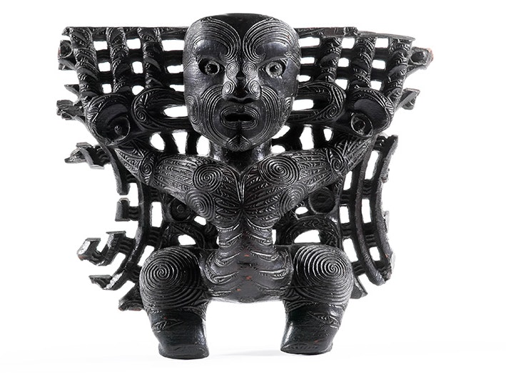 Pare (door lintel), 1800-1850. Oldman Collection. Gift of the New Zealand Government, 1992. Te Papa (OL000044) A dark brown or black piece of Māori wood carving on a white surface.