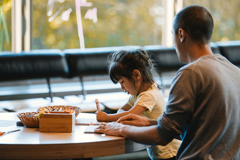 A man and child are sitting at a table doing an art activity.