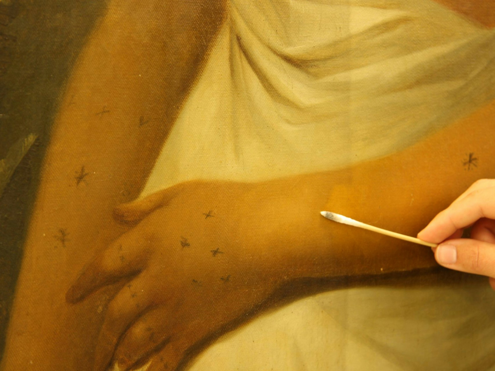 Conservation work on John Webber's Poedua Close up of a conservator's hand holding a cotton bud against a painting.