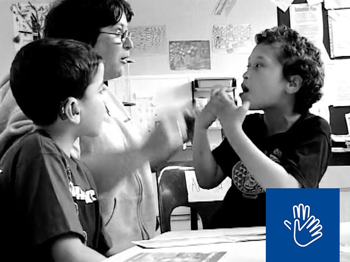 Still from Sign of the Times. Cinematographer Paul Wolffram A black and white image of a teacher signing to a deaf child who is also signing.