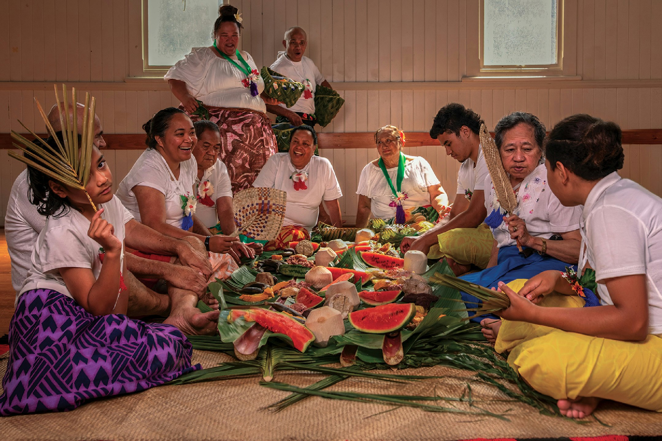People sitting around a feast on a woven mat.